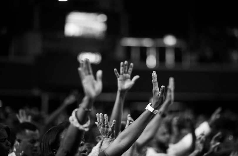 grayscale photography of people raising hands
